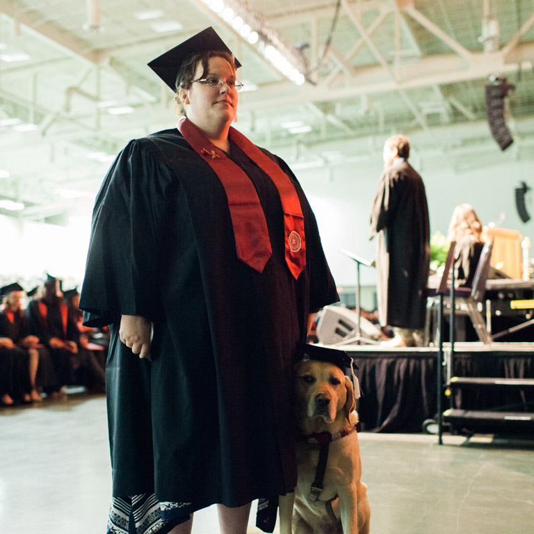 An IU Southeast graduate with her support dog, a golden labrador retreiver.